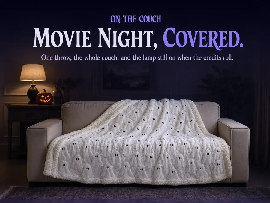 A living room sofa at night with the ghost throw draped across it, a lamp and a small pumpkin lit beside it.