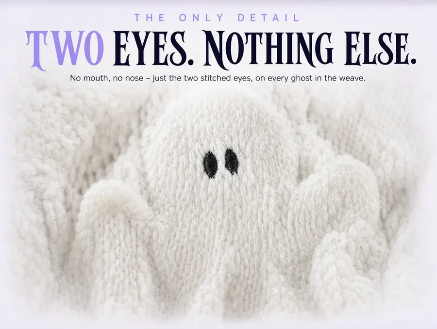 Extreme macro of one raised ghost in the weave, showing only its two small black embroidered oval eyes.