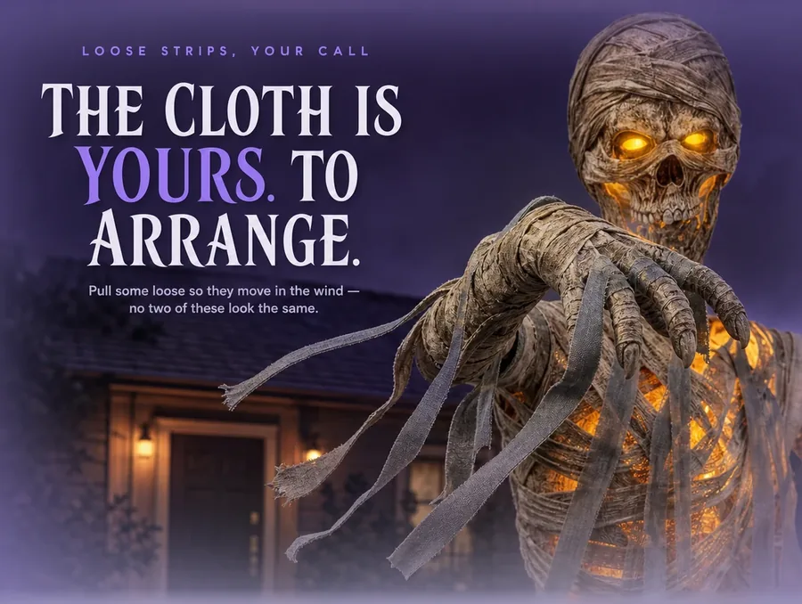 Close crop of loose grey cloth strips hanging from the mummy's shoulder, caught moving in a breeze.
